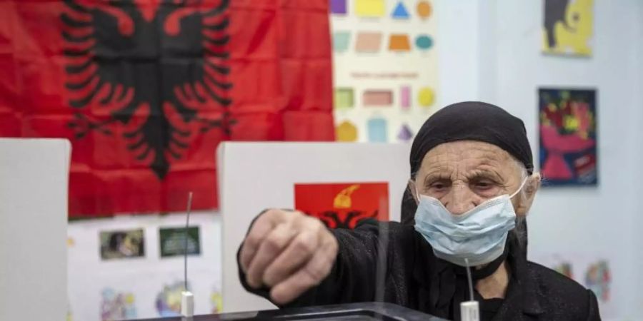 Eine Frau wirft in Tirana ihren Stimmzettel in eine Wahlurne. Foto: Visar Kryeziu/AP/dpa