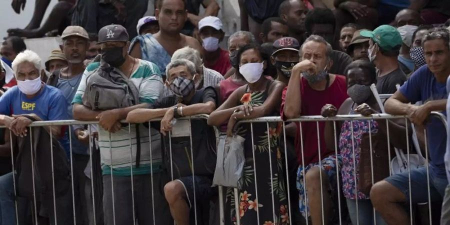 Menschen warten in Rio de Janeiro in einer Schlange auf eine kostenlose Mahlzeit. Foto: Silvia Izquierdo/AP/dpa