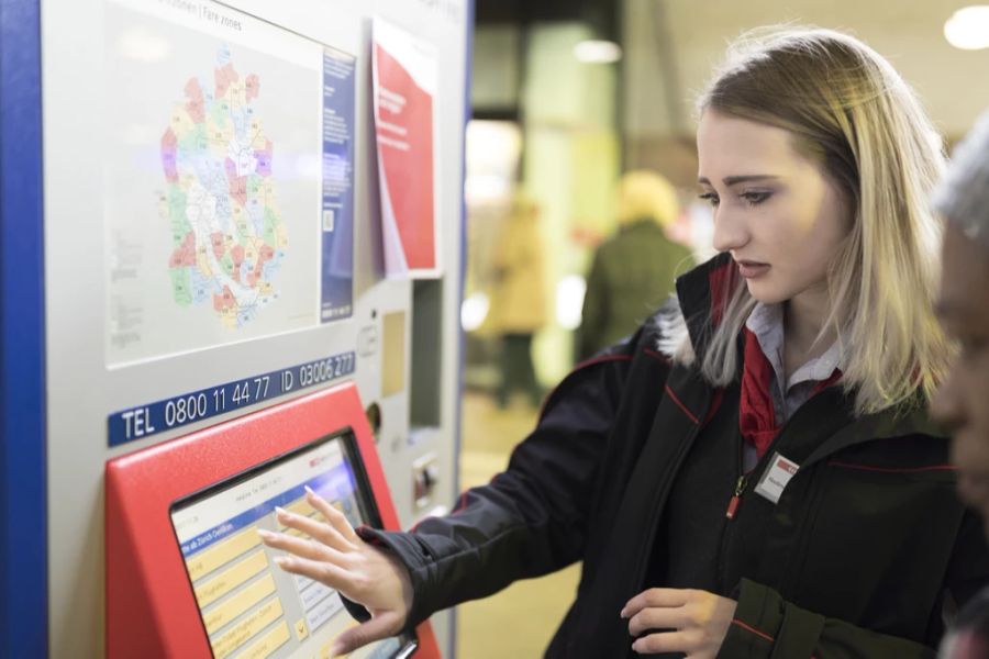 Eine SBB-Mitarbeiterin hilft einem Kunden am Billettautomaten.