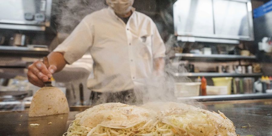 Chefkoch Mitsuo Ise hat für das Gericht «Okonomiyaki», eine Art japanische Pizza, eine spezielle «Deutschland»-Version für Bundeskanzler Scholz mit den Zutaten Würstchen, Kartoffeln und Sauerkraut kreiert.
