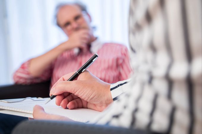 Psychoonkologen sind spezialisiert auf die psychische Versorgung und Betreuung von Krebspatienten und ihren Angehörigen. Stift Block Psychologe Patient Praxis Behandlung