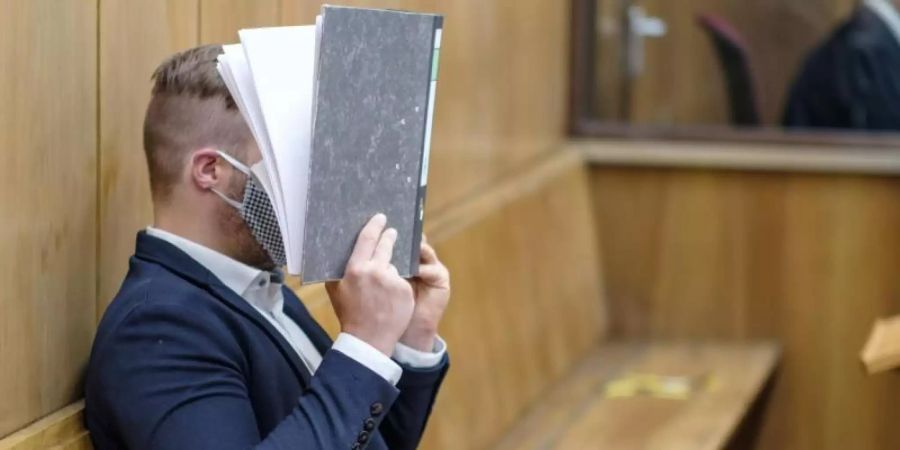 Im Prozess um den Mord an einer jungen Frau hält sich der Anklagte im Landgericht Hannover einen Aktenordner vor das Gesicht. Foto: Ole Spata/dpa