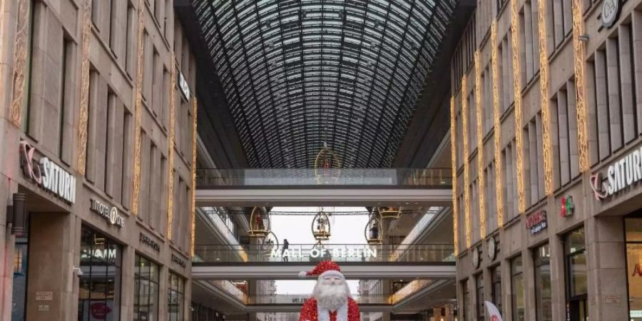 Vor dem Einkaufszentrum «Mall of Berlin» steht eine Weihnachtsmann-Skulptur. Der Bund will in der Corona-Krise schärfere Auflagen für den Einzelhandel. Foto: Christophe Gateau/dpa