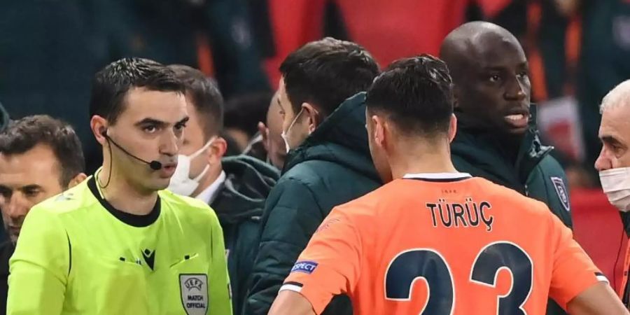 Der rumänische Schiedsrichter Ovidiu Hategan (l) diskutiert mit Verantwortlichen und Spielern von Istanbul Basaksehir und Paris Saint-Germain. Foto: Franck Fife/AFP/dpa