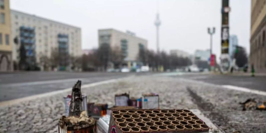 Abgebranntes Feuerwerk liegt auf einer Strasse in Berlin - im Hintergrund der Fernsehturm am Alexanderplatz. Foto: Christophe Gateau/dpa