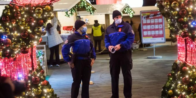 Polizisten kontrollieren die vorzeitige Schliessung des Weihnachtsmarktes auf der Piazza Riforma wegen der nationalen Sperrstunde um 19 Uhr. Maskentragpflicht