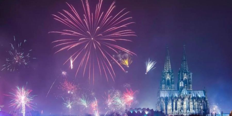 Feuerwerk ist in der Silvesternacht am Rhein über dem Dom zu sehen. Foto: Christophe Gateau/dpa