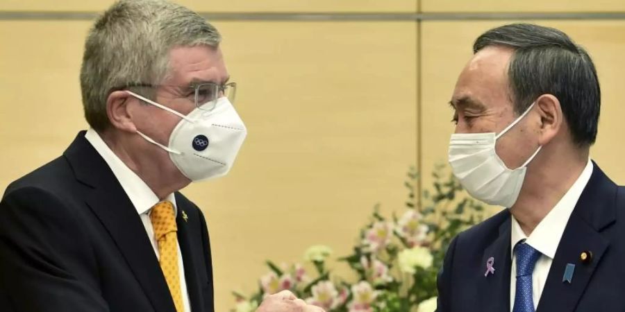 Thomas Bach (l), Präsident des Internationalen Olympischen Komitees, und Yoshihide Suga, Premierminister von Japan, begrüssen sich. Foto: Kazuhiro Nogi/AFP Pool/AP/dpa