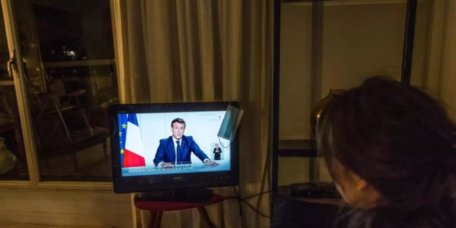 Eine Frau verfolgt in Paris die TV-Ansprache von Staatspräsident Emmanuel Macron. Foto: Sadak Souici/Le Pictorium Agency via ZUMA/dpa