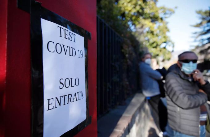 Menschen stehen neben einem Plakat, das anzeigt, wo sie einen COVID-19-Schnelltest zum Mitnehmen erhalten können. Südtirol