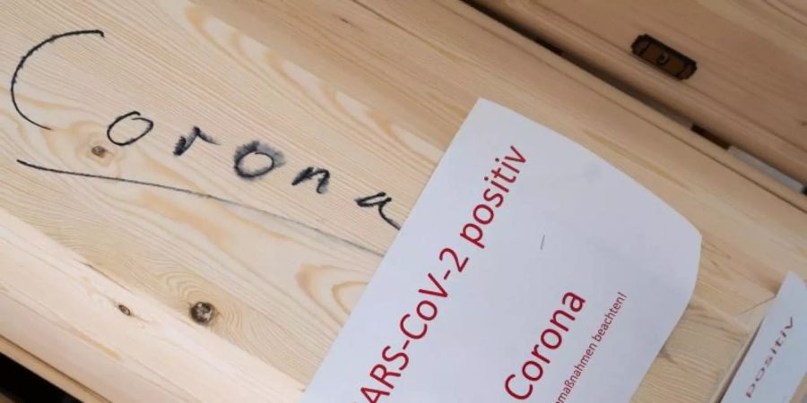 Särge mit Aufschrift „Corona“ und „SARS-CoV-2 positiv - Corona“ mit Verstorbenen in einem Krematorium in Giesen. Foto: Julian Stratenschulte/dpa
