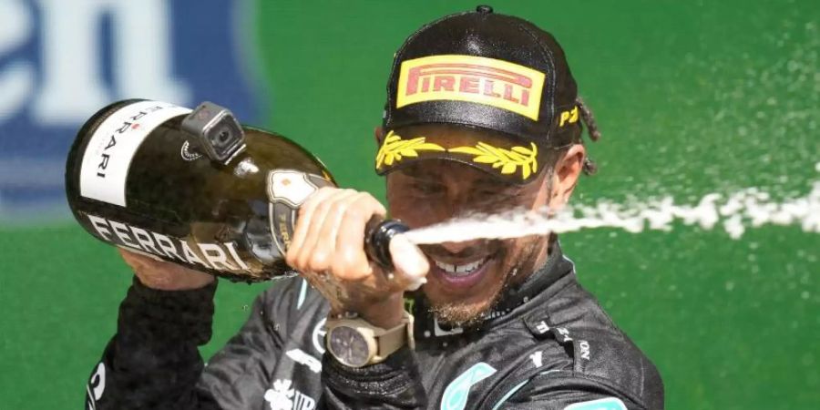 Lewis Hamilton feiert auf dem Podium seinen Erfolg. Foto: Andre Penner/AP/dpa