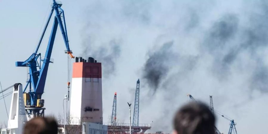 Abgase des Dieselantriebs entsteigen dem Schornstein eines Containerschiffes in Hamburg. Foto: Markus Scholz/dpa