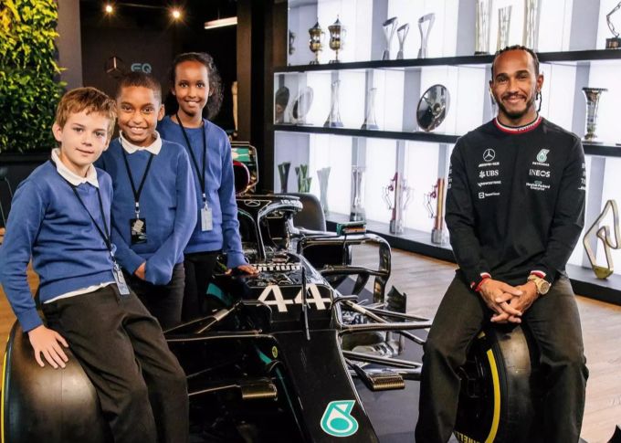 Kieran, Elijah und Hibo (v.l.n.r.) dürfen mit Lewis Hamilton auf einem Mercedes-Renner posieren. Lewis Hamilton Mercedes