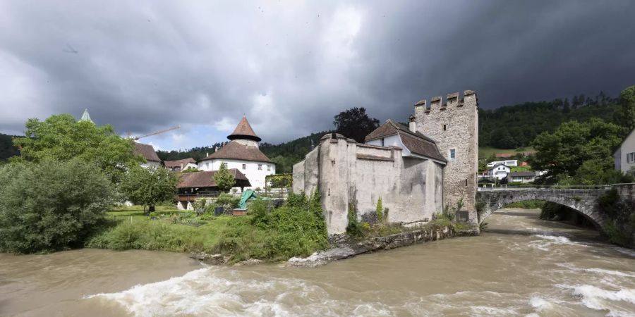 Die Schlossanlage Zwingen an der Birs mit Wehrturm, Bürgerhaus und Holzbrücke.