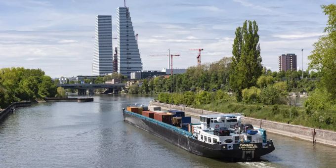 Ein Schiff fährt durch die Schleuse in Birsfelden, im Hintergrund die Stadt Basel. Ein Schiff fährt durch die Schleuse in Birsfelden, im Hintergrund die Stadt Basel.