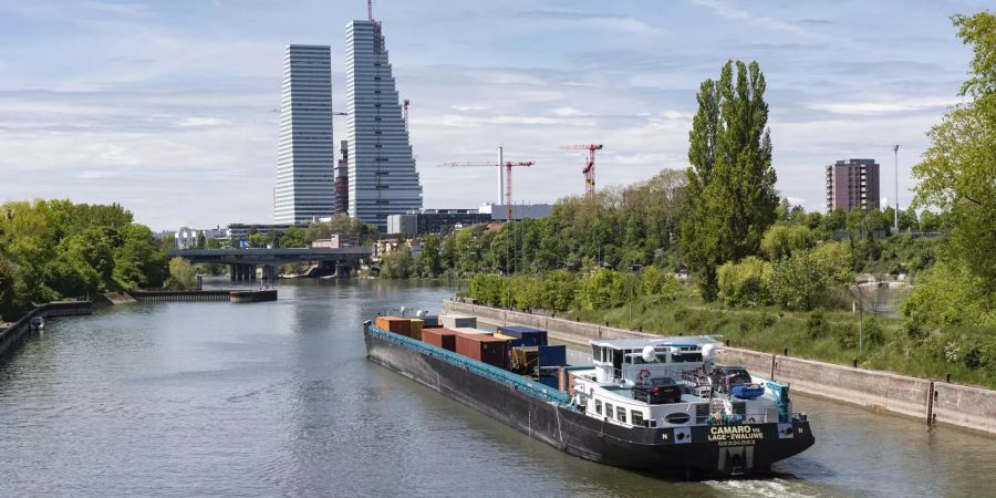 Ein Schiff fährt durch die Schleuse in Birsfelden, im Hintergrund die Stadt Basel.