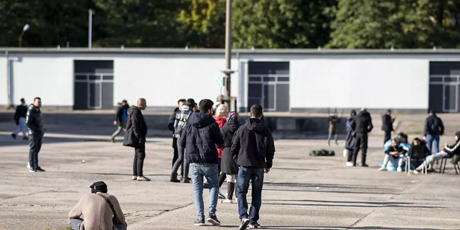 Asylsuchende laufen in der Erstaufnahmeeinrichtung Eisenhüttenstadt über einen Platz. Foto: Fabian Sommer/dpa