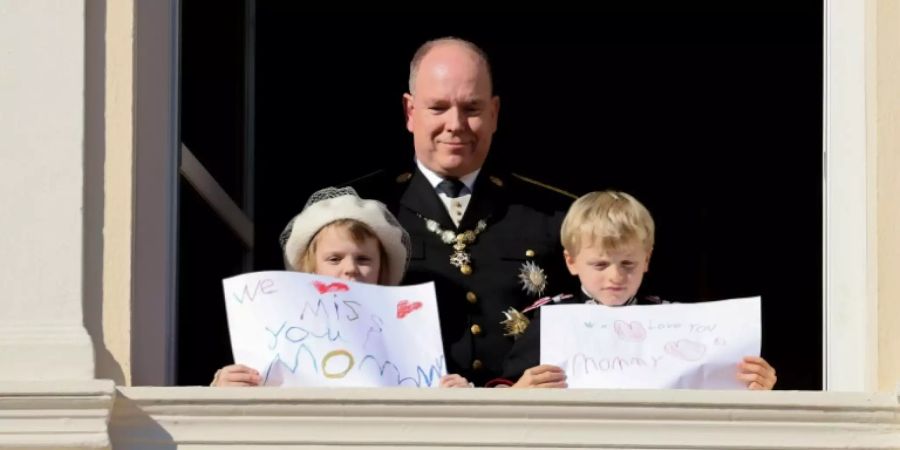 Fürst Albert II. mit seinen Zwillingen. Die Kids halten Schilder für ihre Mutter hoch.