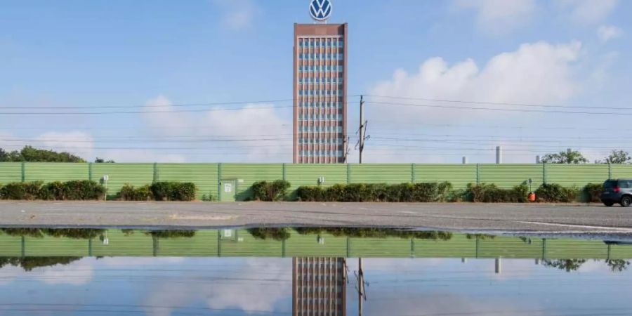 Das Markenhochhaus vom Volkswagen spiegelt sich in einer Pfütze auf einem Mitarbeiterparkplatz vor dem VW Werk Wolfsburg. (Archivbild). Foto: Julian Stratenschulte/dpa