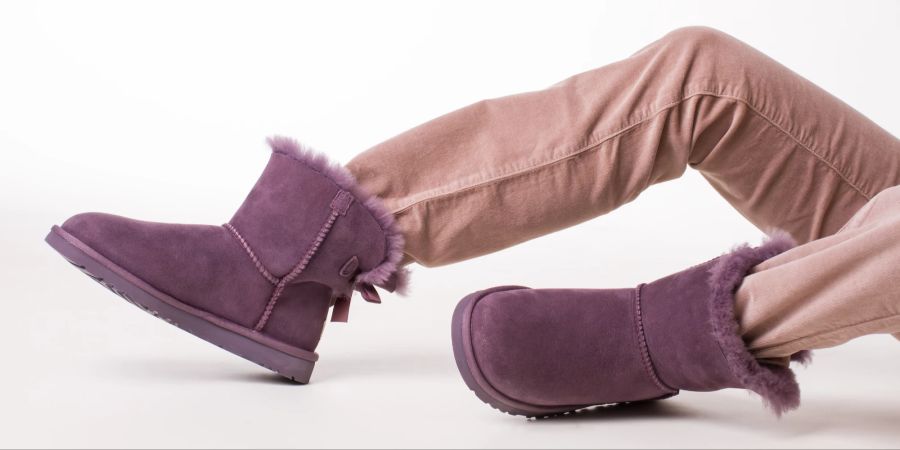 Lila Ugg Boots mit rosa jeansbeinen vor weiss.