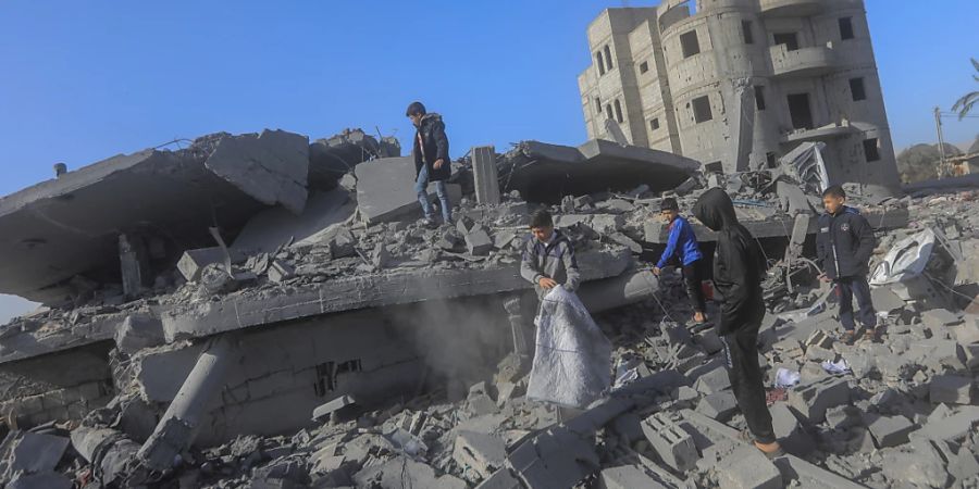 Kinder inspizieren die Trümmer von zerstörten Gebäuden nach israelischem Bombardement. Foto: Mohammed Talatene/dpa