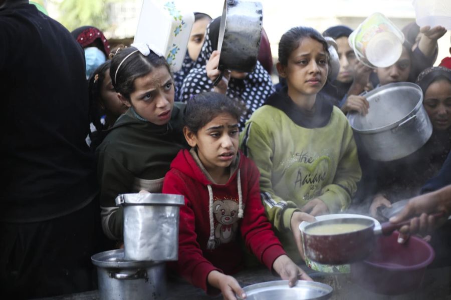 Palästinenserinnen und Palästinenser stehen Schlange für eine kostenlose Mahlzeit in Rafah im südlichen Gaza-Streifen, 20. Dezember 2023. Israel griff an diesem Tag das Flüchtlingslager in Chan Yunis an. §