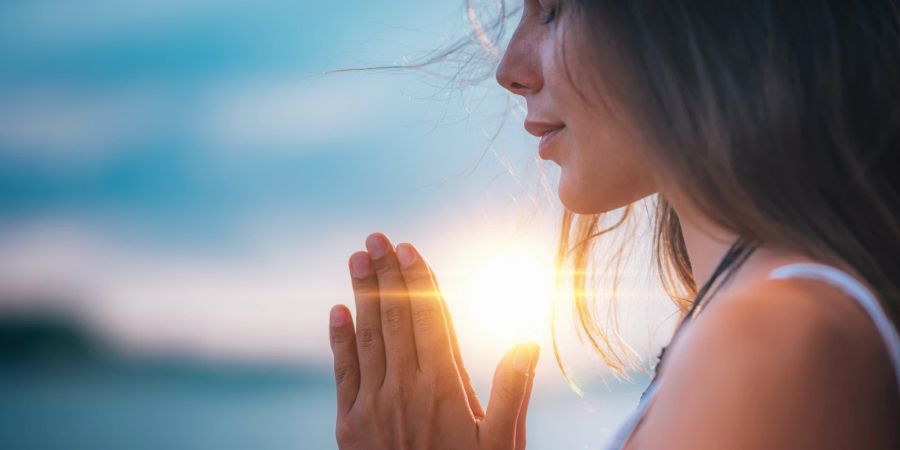 Frau meditiert im Sonnenlicht.