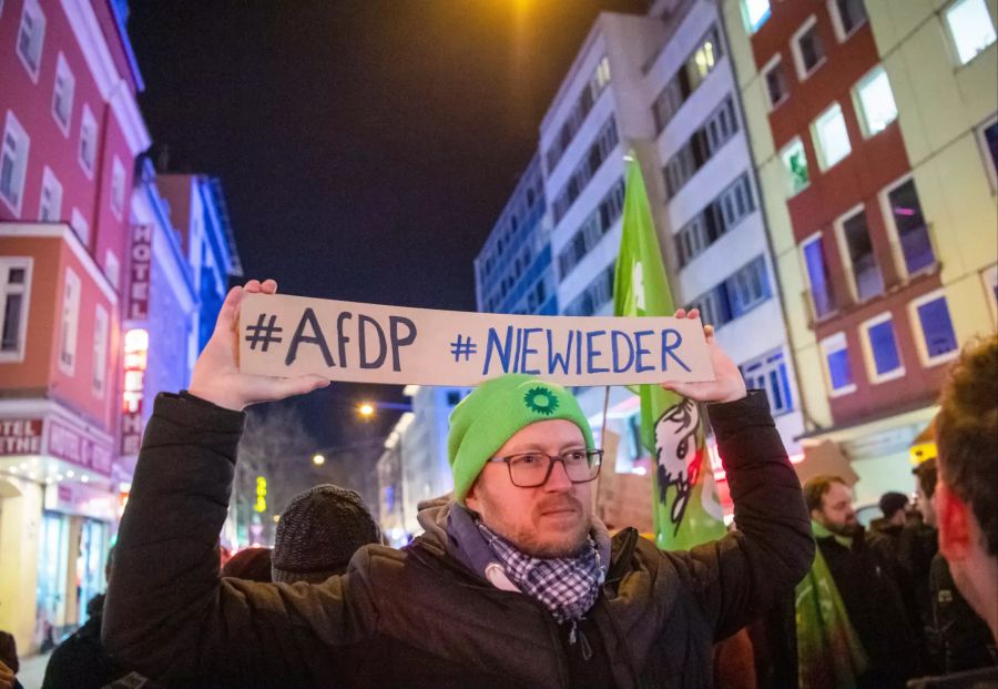 Ein Demonstrant stehen mit einem Plakat mit der Aufschrift «#AfDP #NIEWIEDER» vor der FDP-Geschäftsstelle in München.