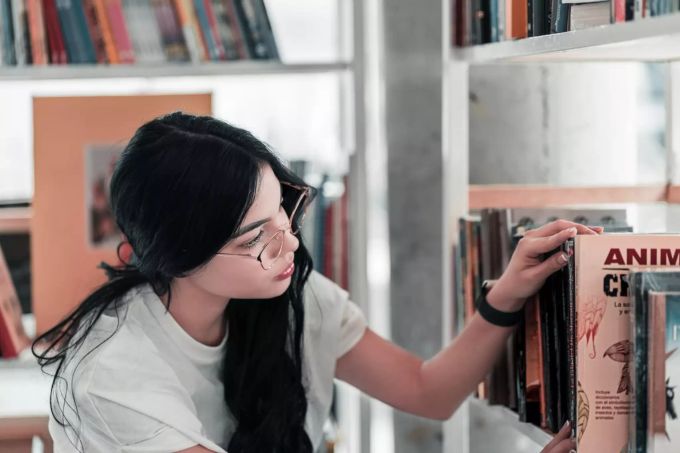 Starten Sie mit Freunden eine Buch-Challenge. Frau in Bibliothek