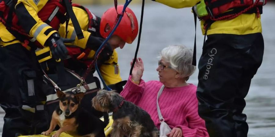 Rettungskräfte bringen eine Frau und ihre Hunde mit einem Schlauchboot in Sicherheit. Foto: Ben Birchall/PA Wire/dpa