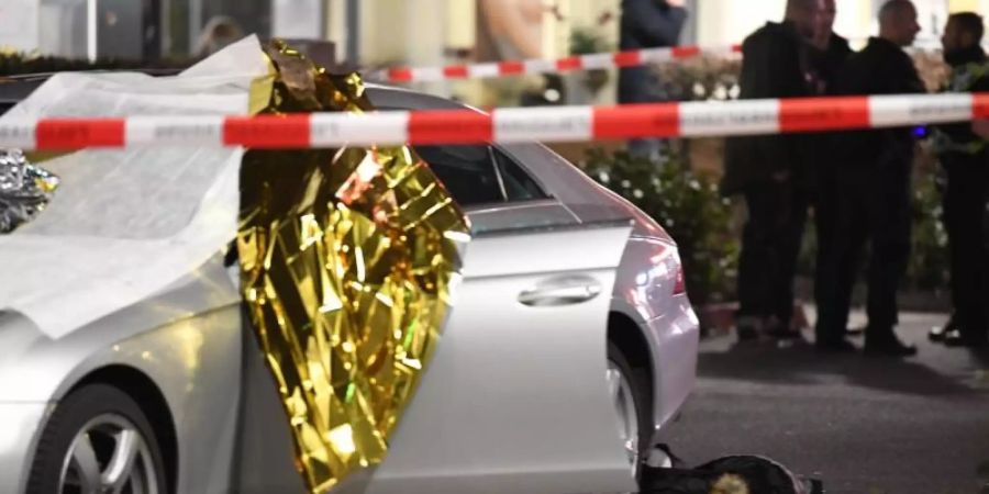 Ein Auto ist mit Thermofolie abgedeckt, neben dem Wagen liegen Glassplitter und eine Jacke. Foto: Boris Rössler/dpa