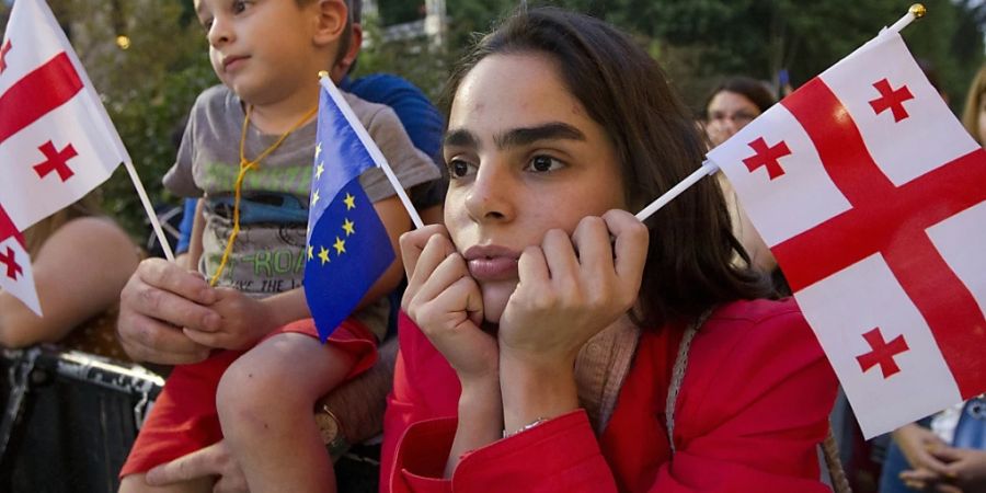 Eine Demonstrantin hält eine georgische Nationalflagge und eine EU-Flagge während einer Pro-EU- und Anti-Regierungs-Kundgebung vor dem georgischen Parlament. Foto: Shakh Aivazov/AP/dpa