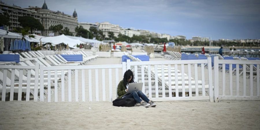 Frau mit Laptop am Strand von Cannes