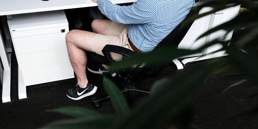 Ein Mann sitzt mit kurzer Hose an seinem Arbeitsplatz. Beschert uns Corona eine neue Lässigkeit?