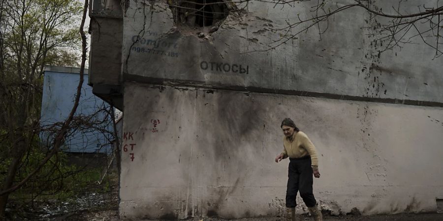 Eine Frau geht nach einem russischen Angriff an einem beschädigten Gebäude in Charkiw vorbei. Foto: Felipe Dana/AP/dpa