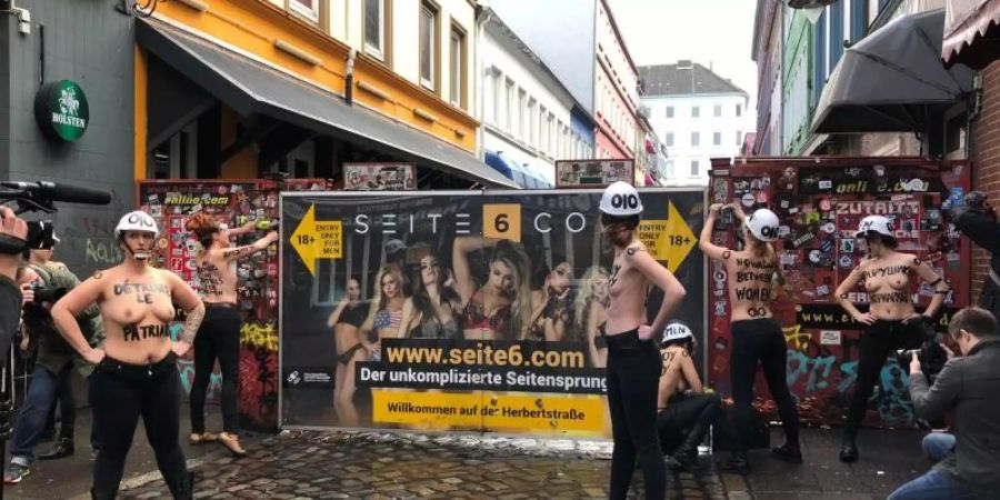 Mit nacktem Oberkörper und einer Flex demontieren Aktivistinnen im Rotlichtviertel von St. Pauli einen Sichtschutz der Herbertstrasse. Foto: Carina Lue