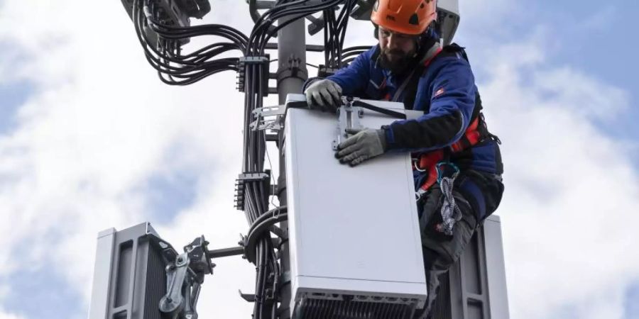 Ein Techniker installiert eine Antenne für das 5G-Funknetz auf einem Hausdach. Foto: Peter Klaunzer/KEYSTONE