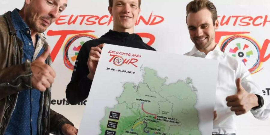 Die Radprofis John Degenkolb (l-r), Nikias Arndt und Maximilian Schachmann zeigen eine Karte mit den Stationen der diesjährigen Deutschland-Tour. Foto: Arne Dedert/dpa