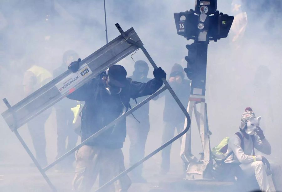 Ein Demonstrant hält eine Absperrung in den Händen.