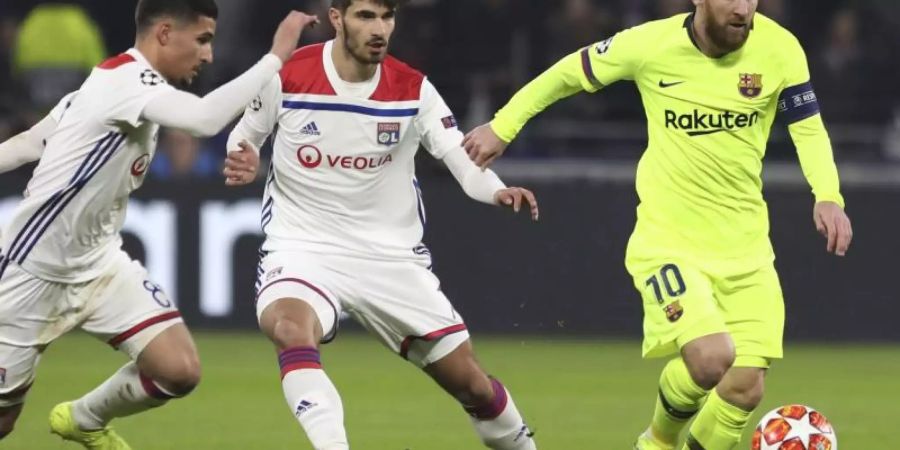 Lionel Messi (r) behauptet den Ball gegen Houssem Aouar (l) und Martin Terrier von Olympique Lyon. Foto: Laurent Cipriani/AP