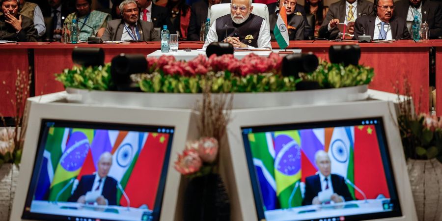 Indiens Premierminister Narendra Modi (M) schaut der Plenarsitzung auf dem Brics-Gipfel 2023 zu, während Kremlchef Wladimir Putin per Videoübertragung spricht.