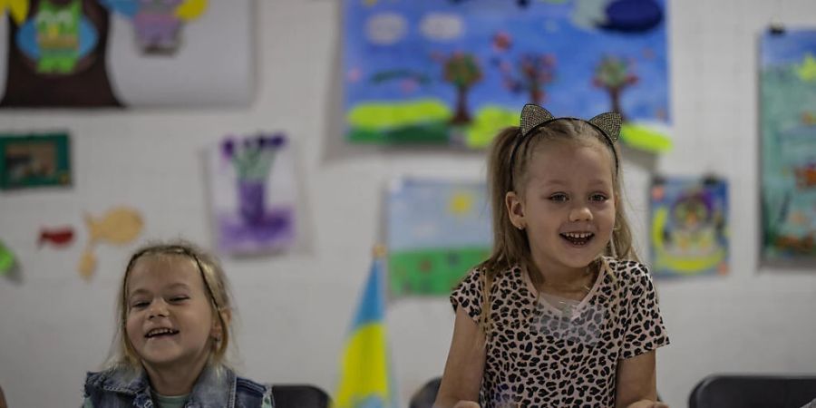 Die fünfjährige Dasha (r) lacht beim Unterricht im «Tato Hub» in Kramatorsk, einer Einrichtung von Freiwilligen für im Kriegsgebiet gebliebene Kinder. Viele Kinder kommen aus Ortschaften, die Brennpunkte des Krieges sind. Foto: Oliver Weiken/dpa