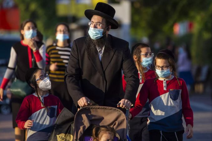 Ultra-orthodoxe Juden warten darauf, eine gesperrte Straße zu überqueren, um zu ihren Häusern zu gehen, während sie Schutzmasken tragen, um die Ausbreitung des Coronavirus in Ashdod, Israel, einzudämmen. (Archivbild) Virus Outbreak Israel