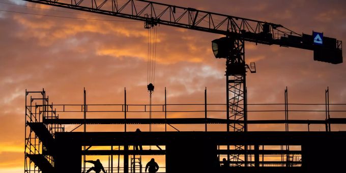 Bauarbeiter arbeiten auf einer Baustelle, während die Sonne aufgeht. schweizerischer baumeisterverband
