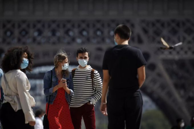 Menschen mit Schutzmaske vor dem Eiffelturm. Auch wenn es viele Neuinfektionen mit dem Coronavirus gibt, ist die Lage weniger schlimm als in der ersten Welle. Coronavirus Frankreich hohe zahlen