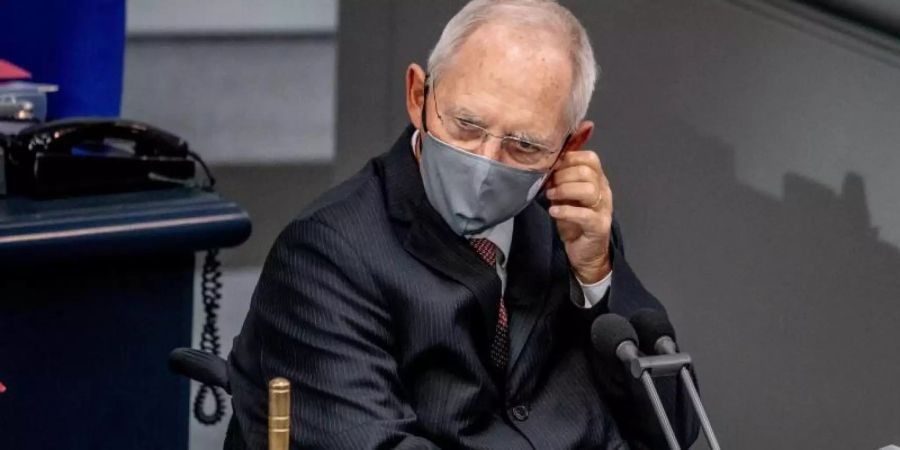 Wolfgang Schäuble (CDU), Bundestagspräsident, nimmt vor der Regierungsbefragung seine Maske ab. Foto: Michael Kappeler/dpa