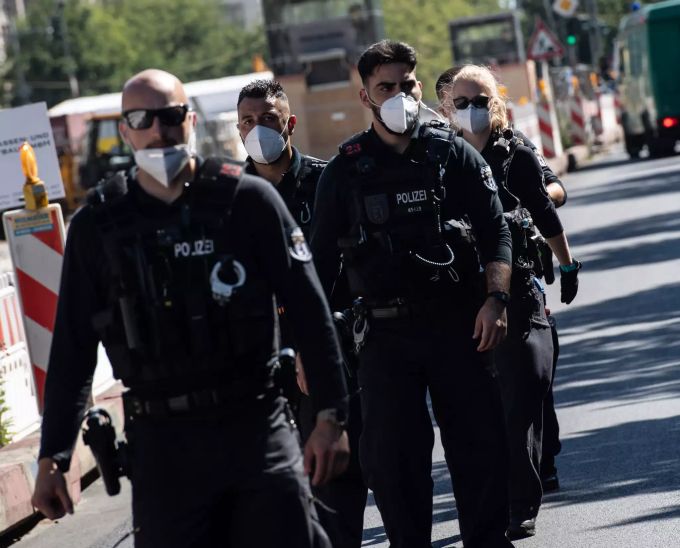 Polizisten mit Mund-Nasen-Schutz gehen vor Beginn der Demonstration gegen die Corona-Massnahmen über den Boulevard Unter den Linden. Foto: Paul Zinken Demonstration gegen Corona-Massnahmen in Berlin