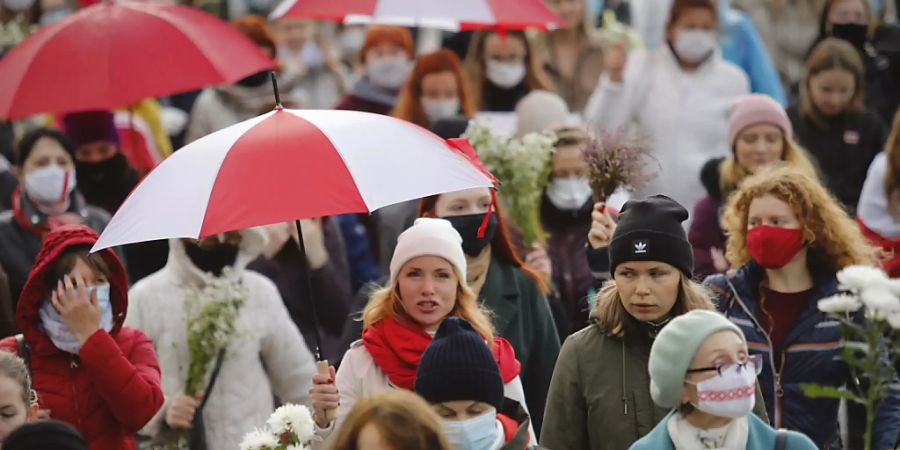 Belarussische Frauen mit Regenschirmen in den Farben der alten belarussischen Nationalflagge. Foto: -/AP/dpa