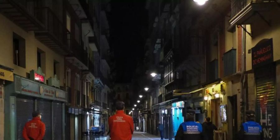 Polizisten patrouillieren auf einer Strasse in Pamplona, bevor alle Bars und Restaurants um 22 Uhr geschlossen werden. Seit Mitternacht gelten deutsche Reisewarnungen für weitere Regionen in 15 EU-Ländern. Foto: Alvaro Barrientos/AP/dpa